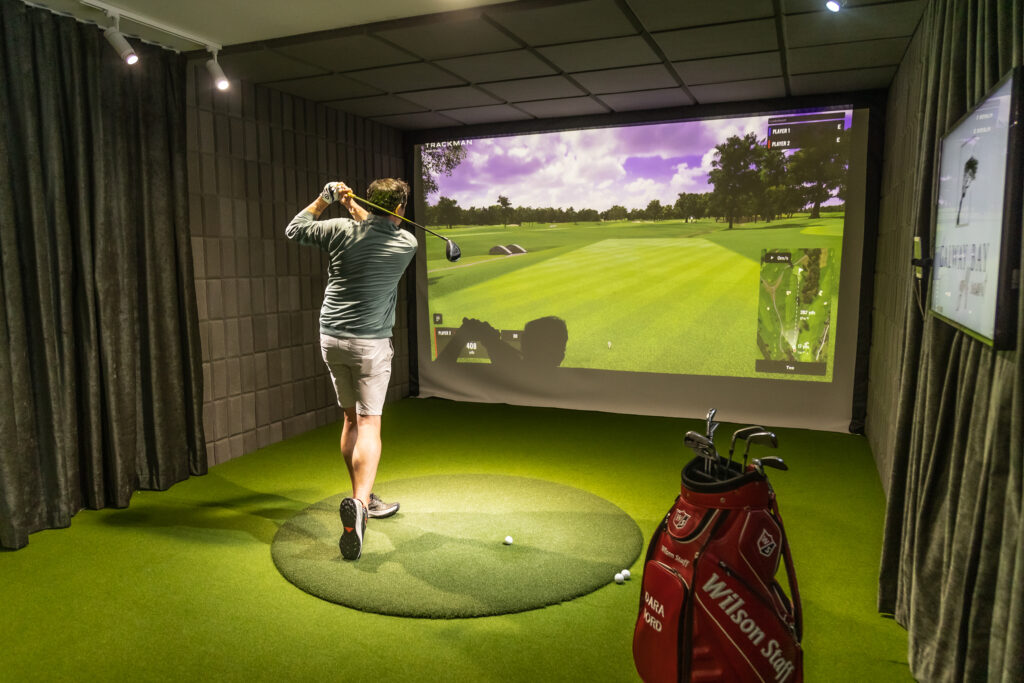 Man standing at indoor golf simulato, the trackman room at Galway Bay Golf Resort